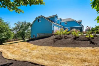 Side yard with fresh landscaping, offering a gentle slope and room for additional garden or outdoor features.