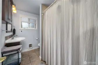 Unit 2 - Spacious full bathroom featuring a wide vanity with updated fixtures, overhead lighting, and extra storage. Neutral tile floors and a large shower/tub combo provide everyday comfort and functionality.