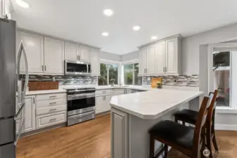 OMG look at this kitchen! This is view one, and I LOVE all of the quartz countertop space, the cabinetry, the breakfast bar area, the included stainless appliances and the full tile backsplash! Not to mention the handy windows behind the sink - who doesn't love those?