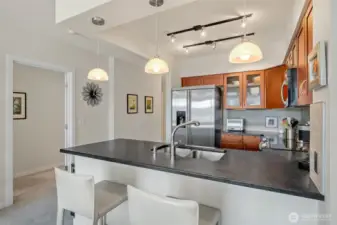 The timeless kitchen features shaker-style cabinetry, honed granite counters with bar-top seating, and stainless steel GE appliances.