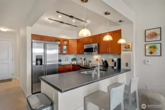 The timeless kitchen features shaker-style cabinetry, honed granite counters with bar-top seating, and stainless steel GE appliances.