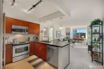 The timeless kitchen features shaker-style cabinetry, honed granite counters with bar-top seating, and stainless steel GE appliances, opening seamlessly to the living area for effortless entertaining.