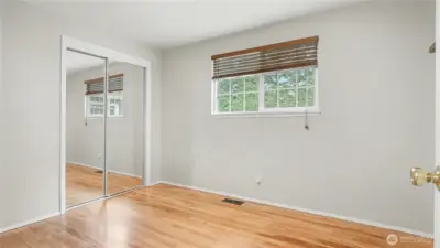 First guest bedroom offering neutral paint color and mirror closet doors.
