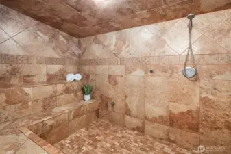 Massive steam shower with multiple seating areas.