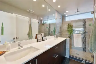 Primary bath includes a large tiled shower with rain shower head and dual sink vanity.