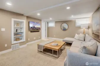 Lower-level media/family room with built-in bookshelves. The TV stays with the home.