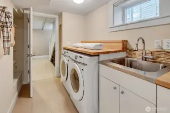 Spacious utility room with brand new washer and dryer, tankless H2O (not shown) a utility sink and custom folding table plus extra storage.