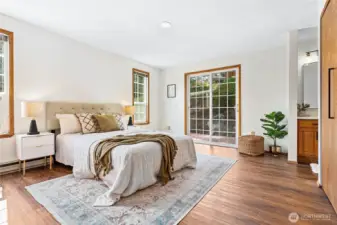 Primary bedroom features a ton of natural light, engineered hardwood floors & step out to back deck.