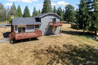 Views on the back of home. Deck off dining room, private deck of primary bedroom and exterior door leads to mudroom/utility room on lower level