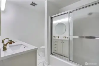 The guest bathroom also includes a convenient shower/tub combo with sliding glass doors—ideal for versatility and function. The updated finishes carry through, offering a cohesive design that blends style with practicality.