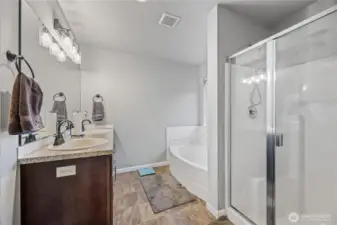 Primary ensuite featuring a dual-sink vanity, soaking tub, and separate glass-enclosed shower. Includes a private water closet and spacious walk-in closet for added comfort and convenience.