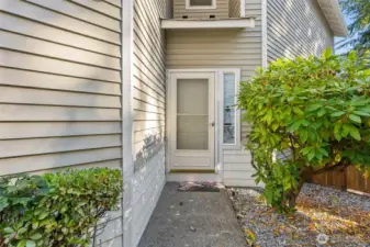 Tucked away entry with shrub lined walkway to front door. Rhododendron shrub next to front door provides beautiful color when in bloom during the Spring.