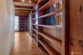 Short hallway off great room to library is lined with custom shelving