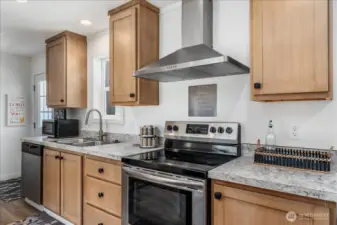 Kitchen w/ stainless steel appliances and hood.