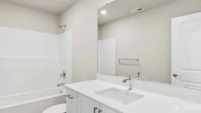 Hall bath with quartz countertops, white cabinets included.