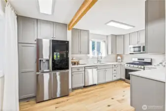 Fully remodeled bright, modern kitchen with Thomasville soft-close shaker cabinetry, updated cabinet hardware, Carrara quartz countertops, LG stainless appliances with dual ice maker, and warm wood accents.