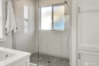 Oversized shower and convenient linen storage complete the room.