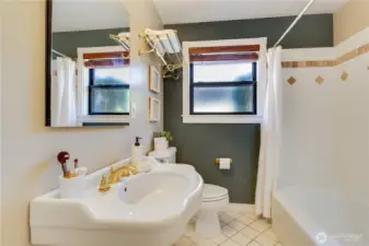 The main floor bath features a pedestal sink, tile floors, and tile shower surround.