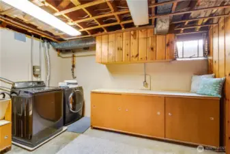 The east side of the basement is an area used for laundry, utilities, a workshop, and storage. The washer and dryer shown here stay with the home.