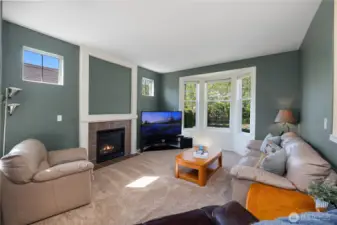 Great room with bright bay windows and gas fireplace leading to dining and kitchen with hardwood floors.