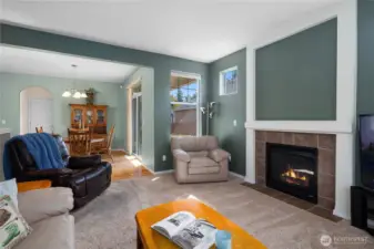 Great room with bright bay windows and gas fireplace leading to dining and kitchen with hardwood floors.