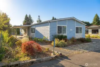 Alternate view of your home with covered outdoor patio on left and backyard access with planter beds and gardening space.