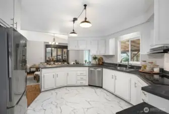 Alternate view of your newly updated kitchen looking towards your dining space. Tons of cabinet space, newer appliances, and countertops. This space feels fresh and new and fully integrated into the living space. Photo is virtually staged.