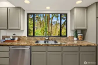 Kitchen sink perfectly positioned beneath a large window capturing peaceful evergreen views