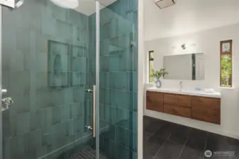 Renovated main floor ¾ bath with designer tile shower and floating vanity, conveniently positioned near the guest room or den