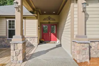 The inviting front-covered entry featuring double doors and stonework, makes a stunning first impression. The front patio overlooks a picturesque field.