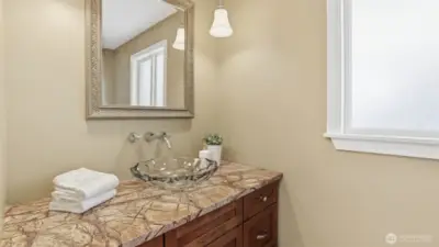 Downstairs powder room with marble countertop and elegant vessel sink.