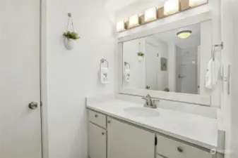 Primary suite with large vanity with quartz countertop, brand new updated shower, & huge linen closet.