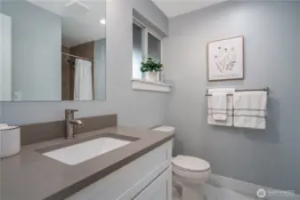 The ensuite 3/4 bath features quartz countertops and white cabinetry.