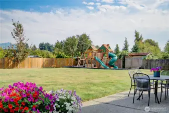Back patio looking towards the playground, foothills beyond, fruit trees on back fence, backyard fully fenced.