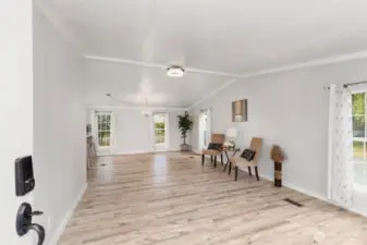 Bright and spacious open-concept living room with updated flooring, fresh paint, and large windows filling the home with natural light.