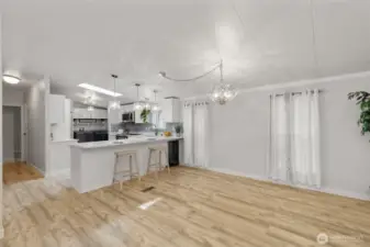 Stylish kitchen with quartz countertops, breakfast bar, pendant lighting, and stainless-steel appliances. Open to dining and living spaces