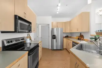 Well-appointed kitchen with abundant counter space, ample cabinetry, and a brand-new stainless steel refrigerator, with easy access to the adjacent pantry and separate laundry room conveniently located off the attached garage.