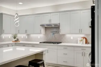 Pot filler and full-height designer tile backsplash add luxury and ease to the cooking zone.