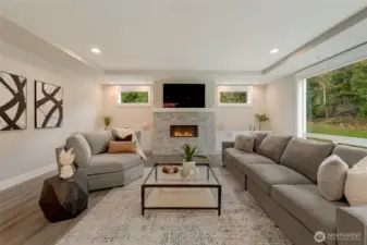 Cozy great room with modern fireplace and built-ins, framed by serene woodland views.
