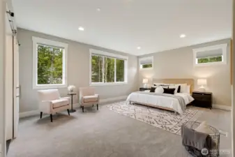 Expansive primary suite with oversized windows framing lush greenery and abundant natural light.