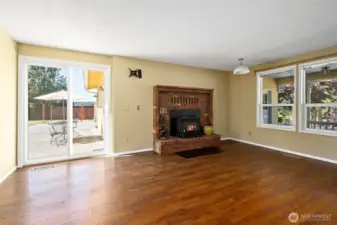 Living area with woodstove and slider that leads to a massive backyard.