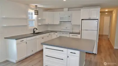Remodeled Kitchen w/ LVP flooring, painted butcher block counters, appliances, and classic while tile backsplash with some floating shelves.