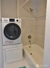 Guest Bathroom w/ washer/dryer combo unit. Tiled walls around the tub.