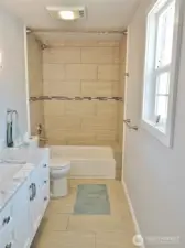 Remodeled Master Bathroom w/ tile floors, vanity, and tiled walls around the tub.