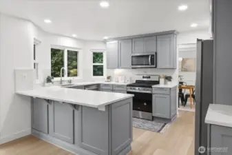 Fully renovated kitchen with quartz counters, full-height backsplash, premium shaker cabinets, pantry, deep drawers, and updated stainless steel appliances.