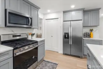 Fully renovated kitchen with quartz counters, full-height backsplash, premium shaker cabinets, pantry, deep drawers, and updated stainless steel appliances, including gas cooktop.