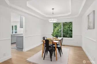 Formal dining room with tray ceiling and chair rail molding, luxury vinyl plank flooring, fresh paint & craftsman trim. Doorway directly to the fully renovated kitchen.