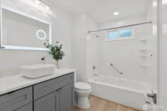Updated vanity with grey shaker cabinets and drawers. Lux Hardwired LED Mirrors with Color Changing Temperature with a built in Magnifier, convection wall heater, new toilet, luxury vinyl plank flooring, craftsman trim.