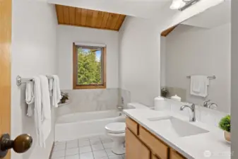 Shared bath on main level with new tile surround on bath and new quartz countertops.