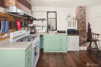 Unit #2015: With exposed brick and reclaimed wood accents, the updated kitchen brings modern convenience to the 1906 original charm. The door to the basement is visible in the far right corner of this photo.